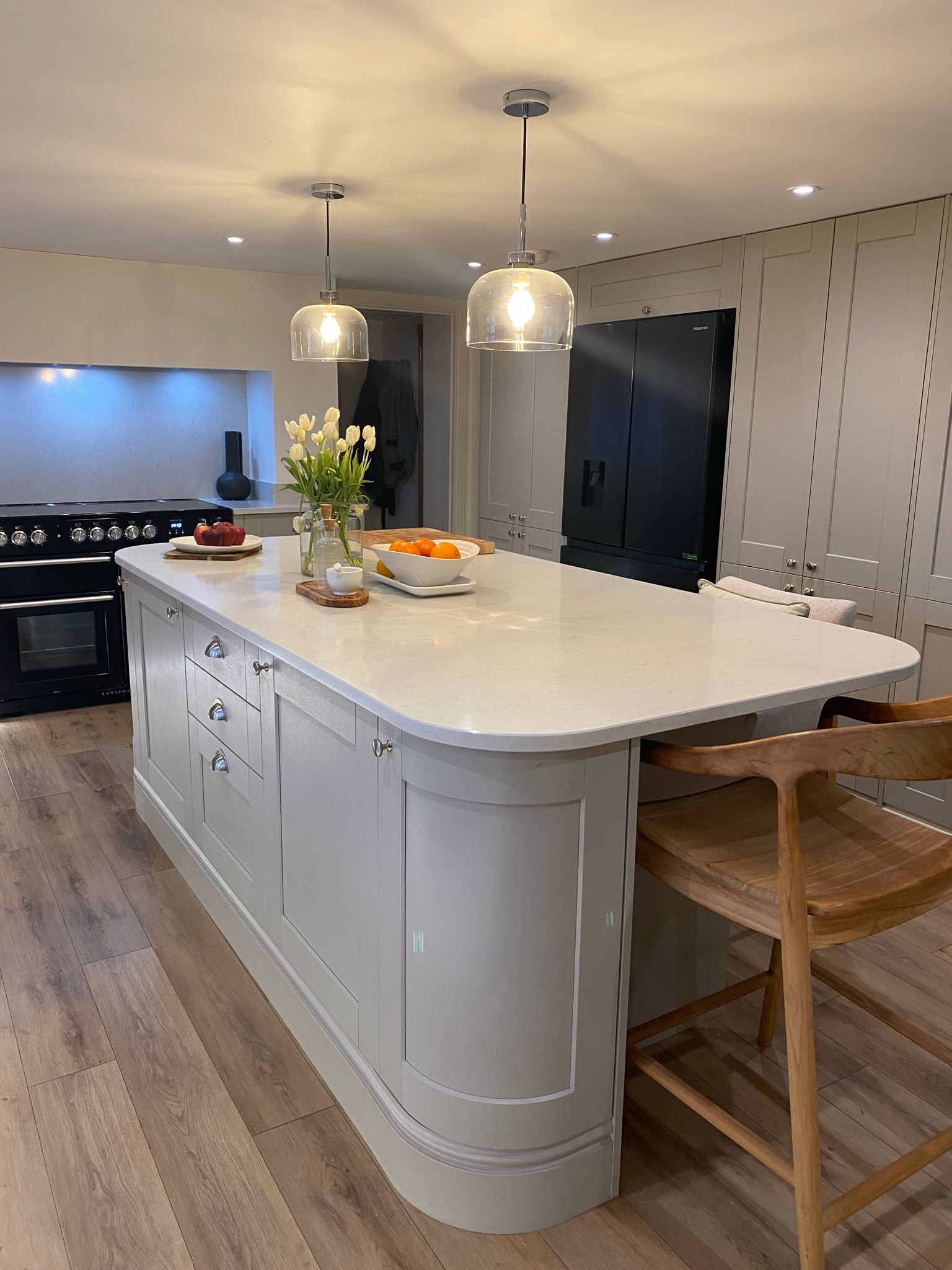 Neutral kitchen island with pendant lights and fitted cabinetry